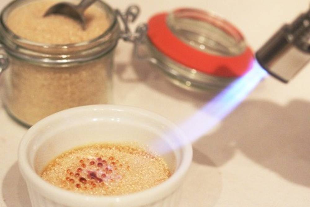 Mit dem Bunsenbrenner Crème brûlée karamellisieren. Mit dem Bunsenbrenner Crème brûlée karamellisieren.
