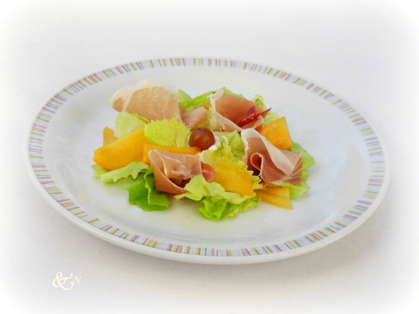 Kaki mit Prosciutto serviert mit einer Senf-Haselnussvinaigrette