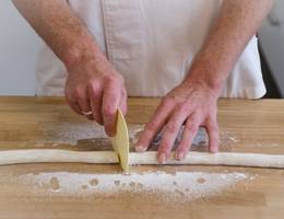 Schritt 12: Die Marzipanrolle in der Mitte auseinanderschneiden. Schritt 12: Die Marzipanrolle in der Mitte auseinanderschneiden.