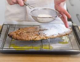 Schritt 40: Den Christstollen sofort dick mit Staubzucker bestreuen. Schritt 40: Den Christstollen sofort dick mit Staubzucker bestreuen.