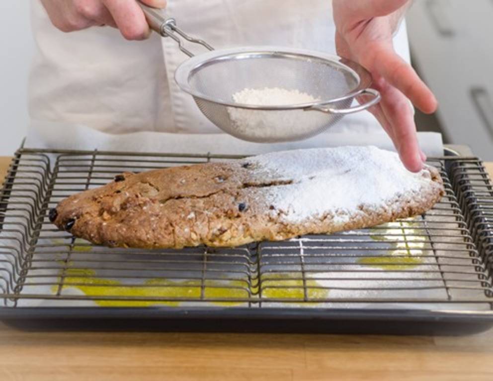 Schritt 40: Den Christstollen sofort dick mit Staubzucker bestreuen. Schritt 40: Den Christstollen sofort dick mit Staubzucker bestreuen.
