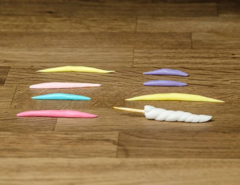 Schritt 2: Mähne und Schwanz aus buntem Rollfondant formen. Das Horn wurde einfach um einen Zahnstocher gewickelt. Schritt 2: Mähne und Schwanz aus buntem Rollfondant formen. Das Horn wurde einfach um einen Zahnstocher gewickelt.
