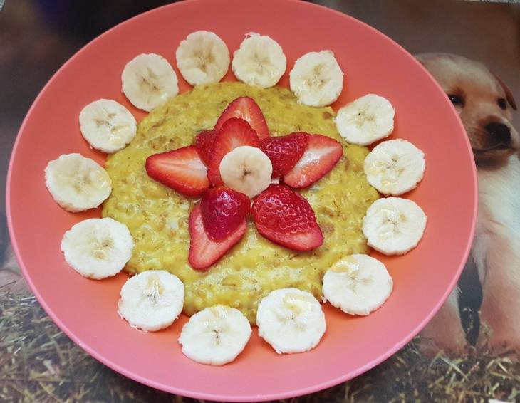 Goldener Frühstücksbrei mit Erdbeeren und Banane