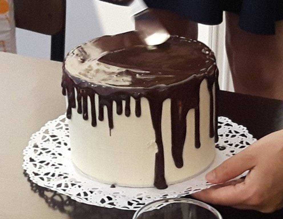 Die restliche Kuvertüre auf die Oberfläche der Torte spritzen und mit einer Palette möglichst glatt verstreichen. Die restliche Kuvertüre auf die Oberfläche der Torte spritzen und mit einer Palette möglichst glatt verstreichen.