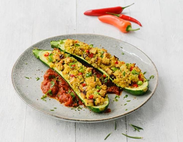 Mit Quinoa gefüllte Zucchini auf scharfem Tomaten-Ragout