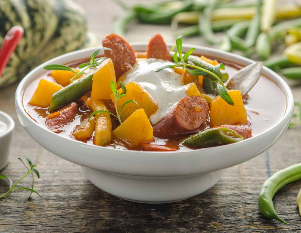 Kürbisgulasch mit Fisolen, Debrezinern und Kümmelrahm Kürbisgulasch mit Fisolen, Debrezinern und Kümmelrahm