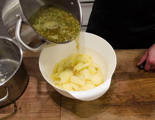 <p>Die Suppe zu den in Scheiben geschnittenen Erd&auml;pfeln hinzugeben.</p>