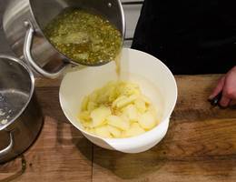 <p>Die Suppe zu den in Scheiben geschnittenen Erd&auml;pfeln hinzugeben.</p>