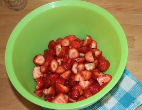 Für die Erdbeermarmelade die Erdbeeren waschen, das Grün entfernen und die Früchte in kleine Stücke schneiden.
