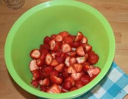 Für die Erdbeermarmelade die Erdbeeren waschen, das Grün entfernen und die Früchte in kleine Stücke schneiden.