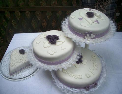 Mehrstöckige Hochzeitstorte mit violetten Rosen und weißen Herzen